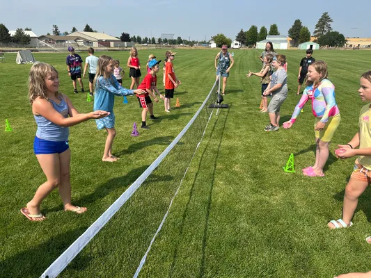Youth lined up on both sides of a net tossing water balloons back and forth