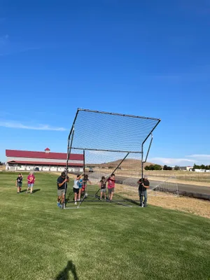 Youth and leaders moving the wheeled backstop into place on the field