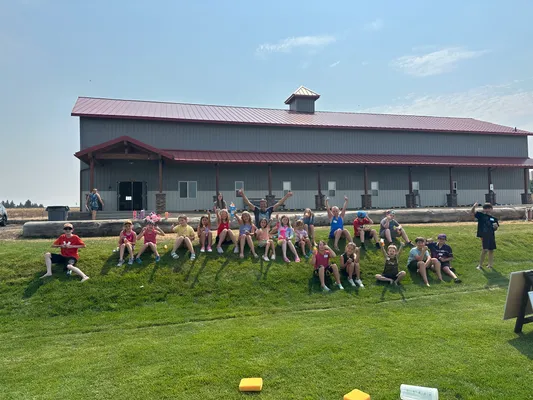 Large group of youth cheering on the grass in front of the Epic Youth Center