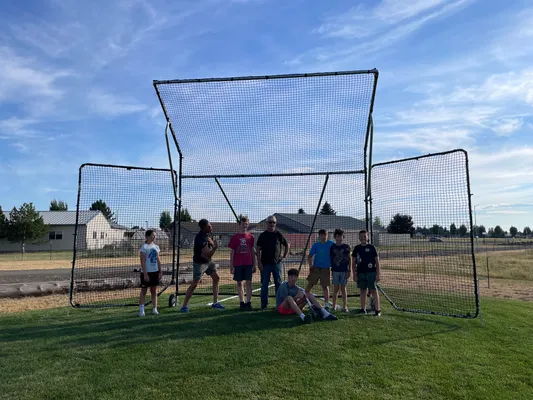 Group of youth and leaders posing in front of the newly assembled softball backstop