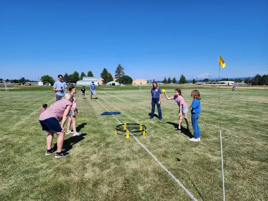 Youth in a circle bouncing a ball off a net.