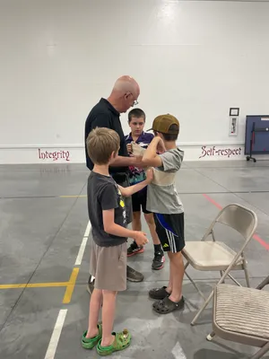 Instructor helping youth wrap a bandage around a classmate's arm