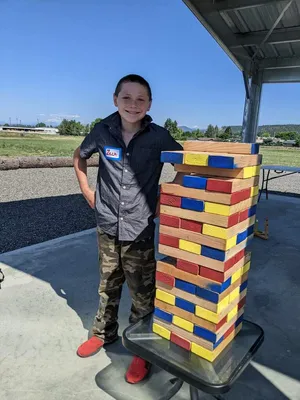 Youth beside a giant Jenga tower.