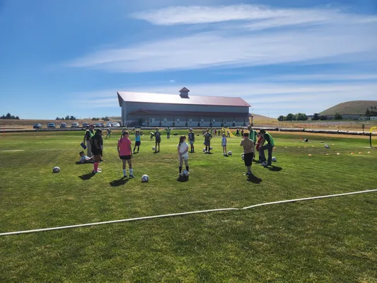 Group of campers gathered on the field with soccer balls during camp