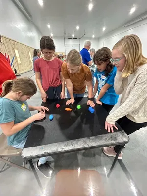 Youth gathered around a table with small colored items on it