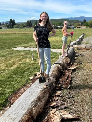 Youth standing on logs and peeling bark off