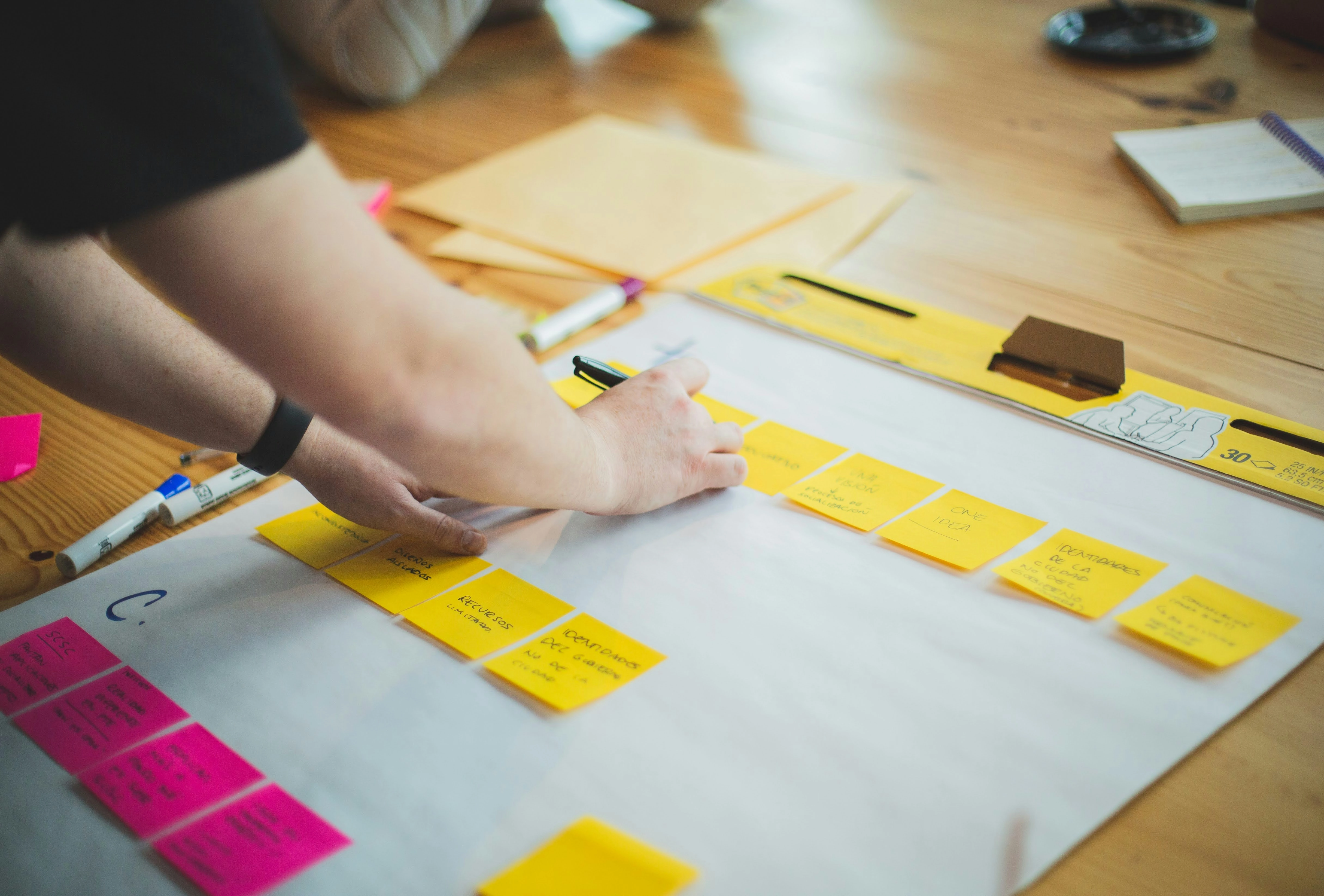 Board with sticky notes on it and a person writing on one with a sharpie