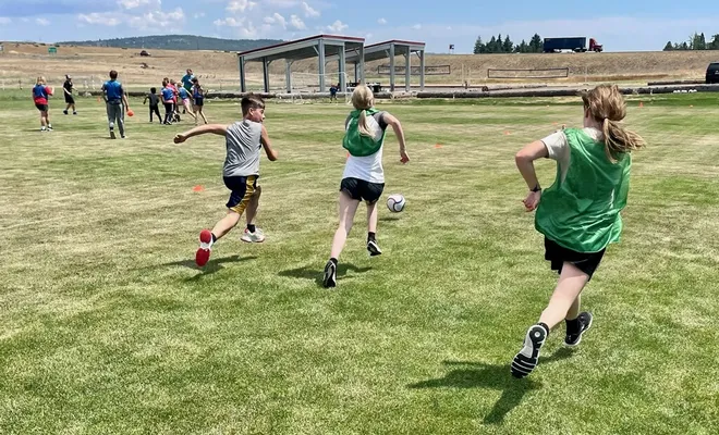 Youth chasing a soccer ball.