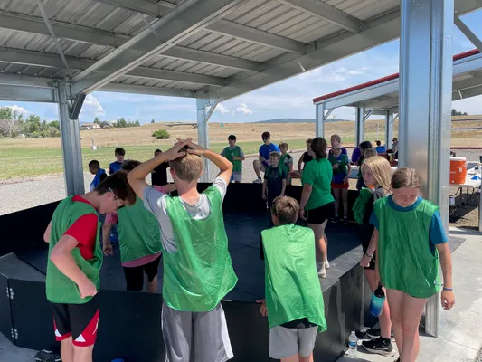 Youth in green jerseys around a ring.