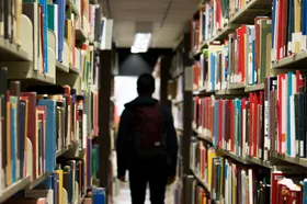 A youth walking between shelves in a library